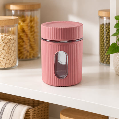 A pink ribbed storage jar with a clear window sits empty on a white shelf, surrounded by other food containers.