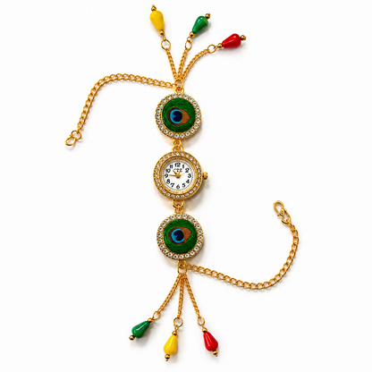 A gold-tone bracelet watch with two peacock eye designs, a central watch face, and colorful dangling beads is laid flat on a