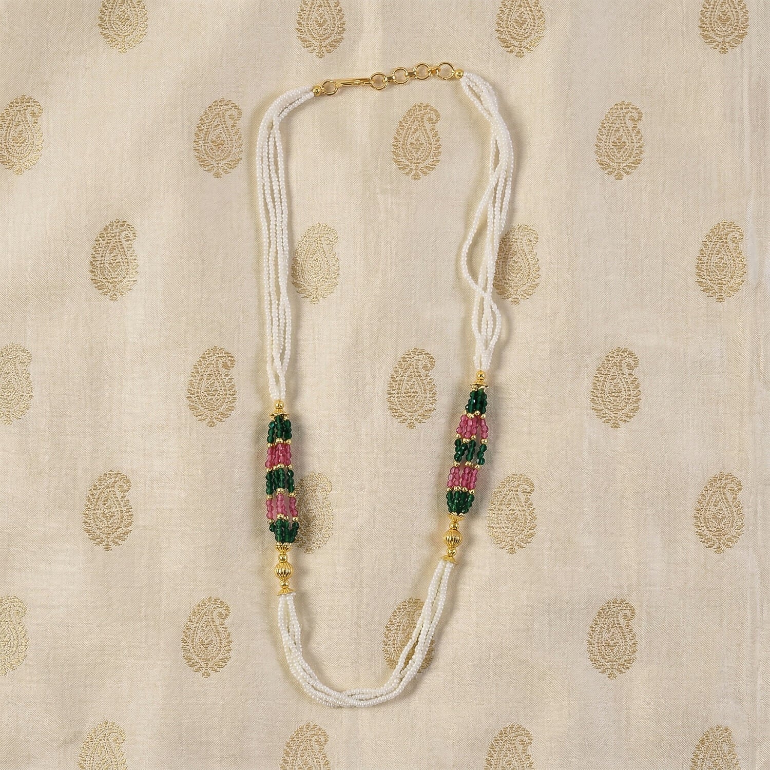 Close-up of green and pink bead details on white mala necklace
