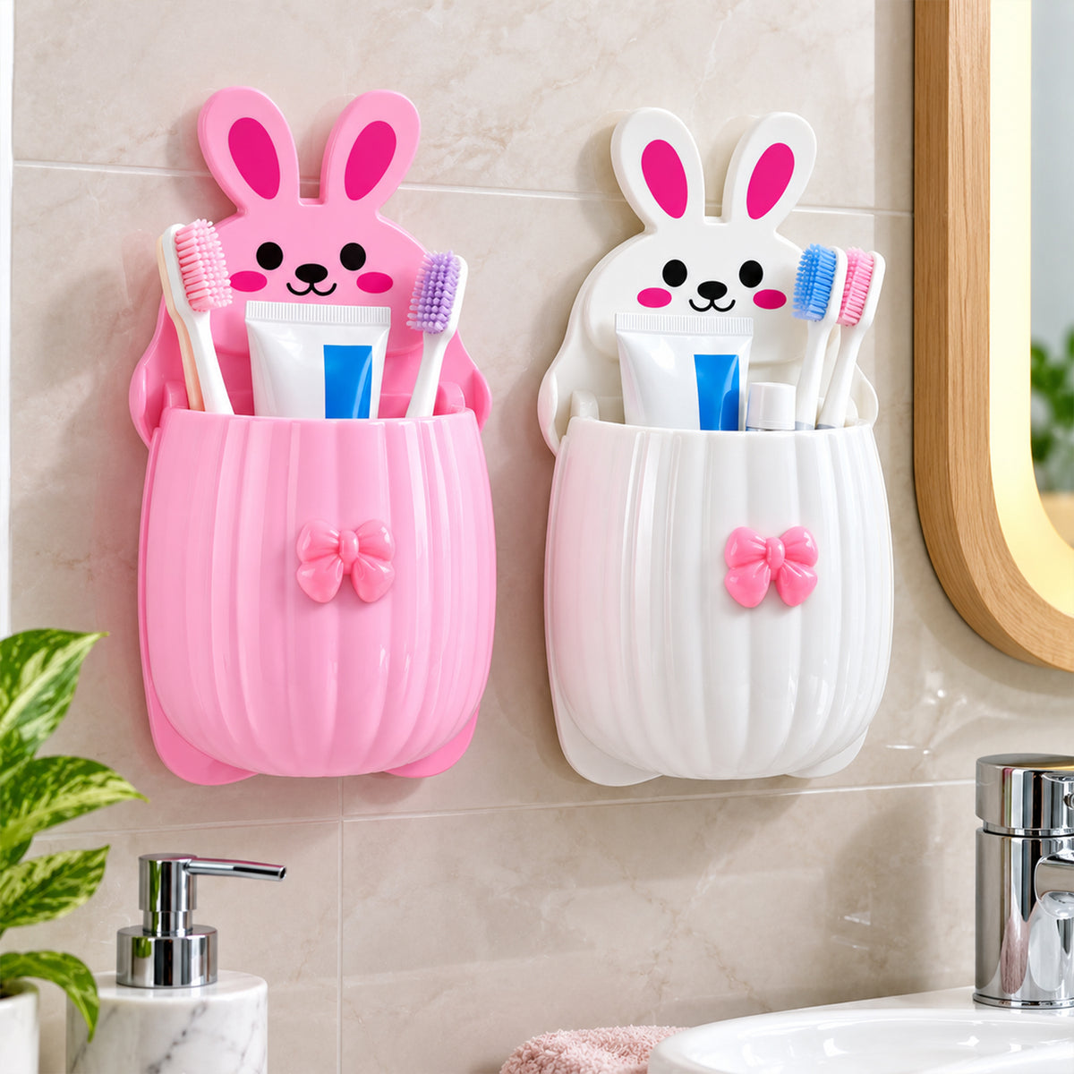 Two wall-mounted rabbit organizers, one pink and one white, holding toothbrushes and toothpaste above a bathroom sink.