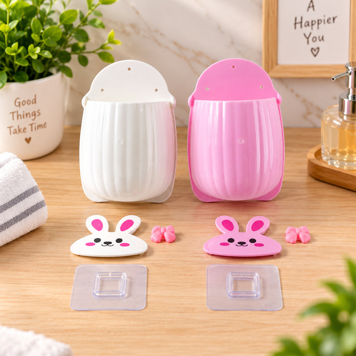 Disassembled pink and white rabbit organizers with separate faces, bows, and clear adhesive hooks on a wooden surface.