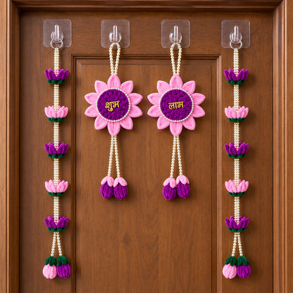 Four pink and purple lotus flower hangings with pearl beads on a closed brown wooden door.