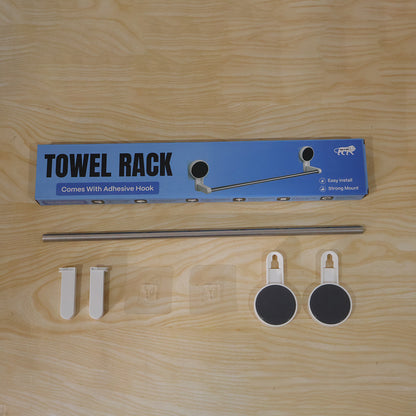 The towel rack packaging and components are laid out on a wooden surface, including the box, rod, end pieces, and hooks.