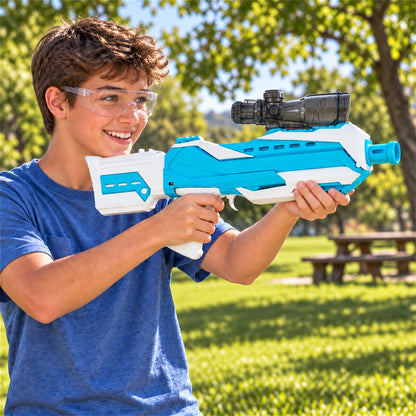 A boy with safety glasses smiles while holding a blue and white gel blaster outdoors on a sunny day.
