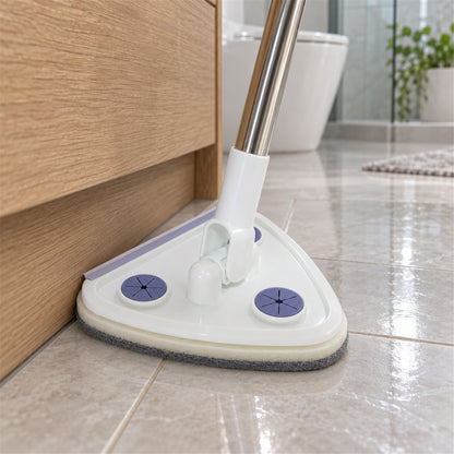 Close-up of the white triangular mop head with purple accents, cleaning a tiled floor next to a wooden cabinet.