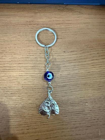 Om leaf evil eye keychain held in a person's hand