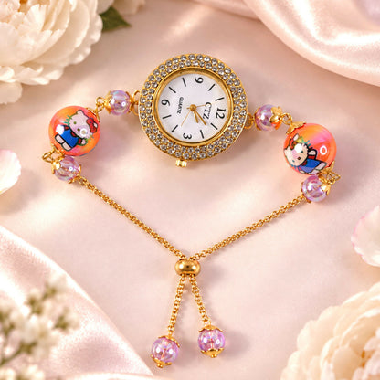 A gold-tone bracelet watch with a rhinestone-encrusted dial, featuring two large orange beads with cartoon characters and
