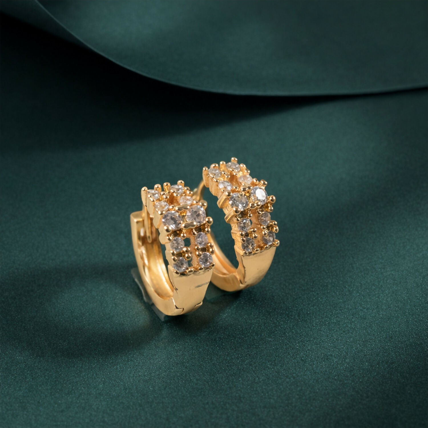 Close-up of gold-tone crystal hoop earrings with polished finish
