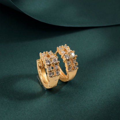 Close-up of gold-tone crystal hoop earrings with polished finish
