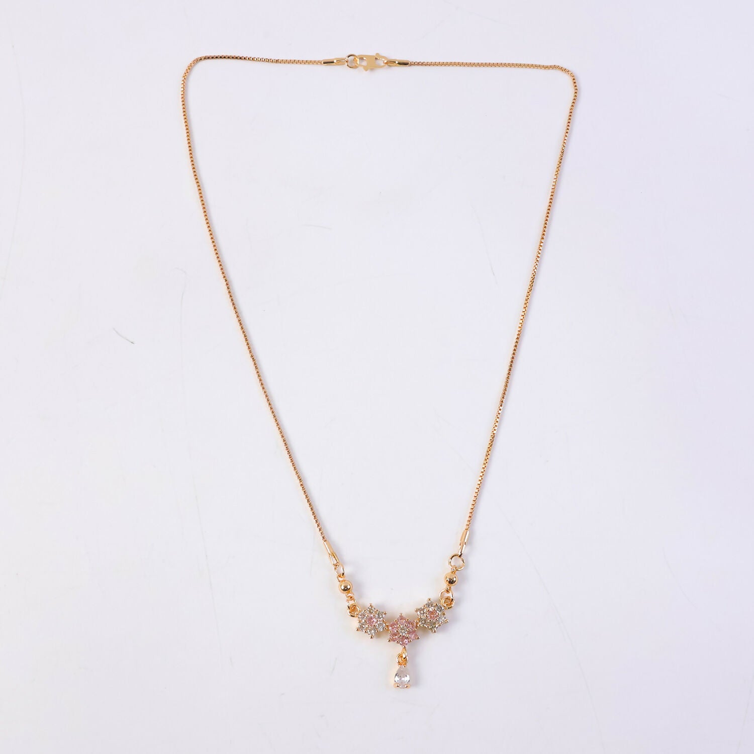 Side angle of gold finish floral stone necklace with detailed pendant design
