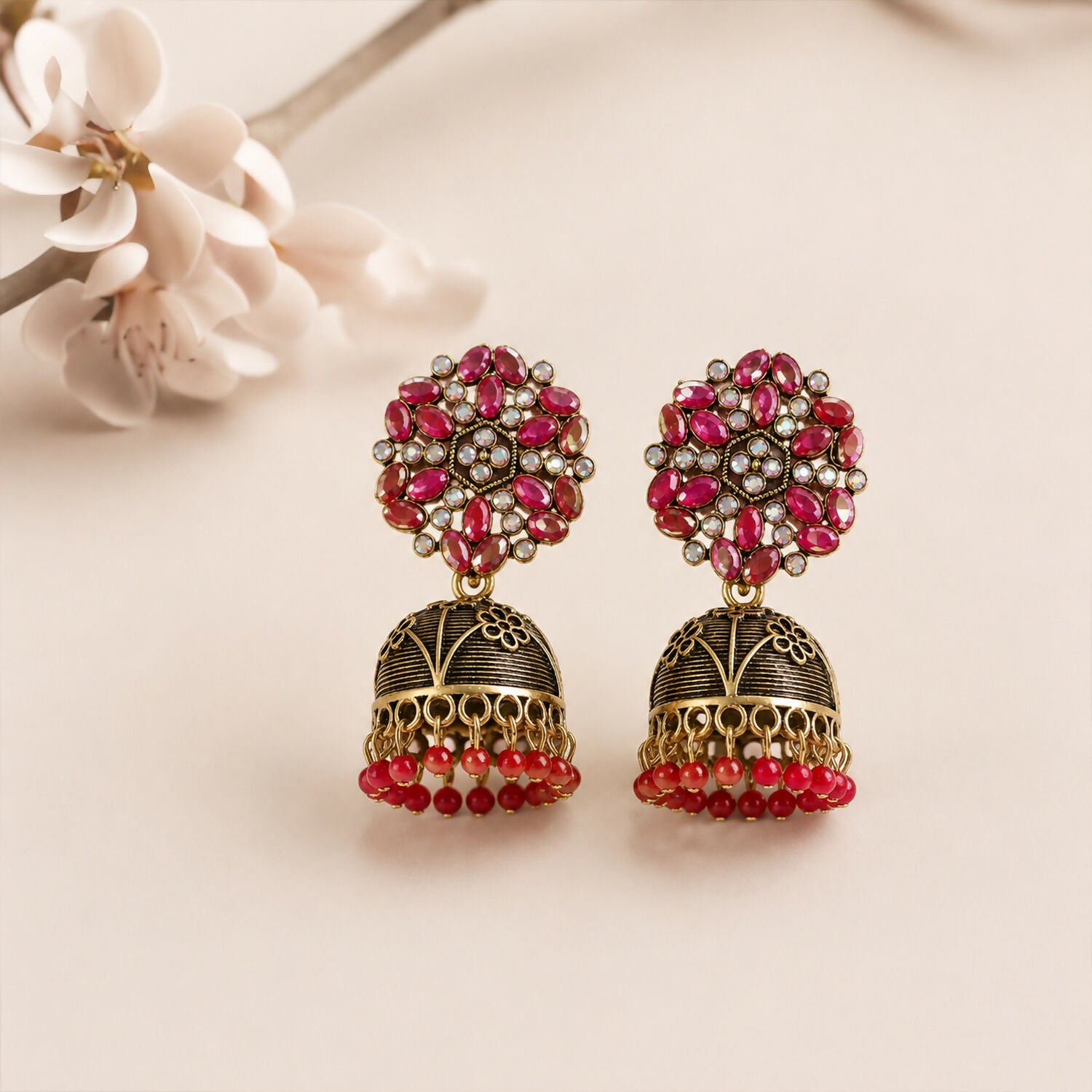 Close-up of jhumka earrings showing pink floral stone and golden dome