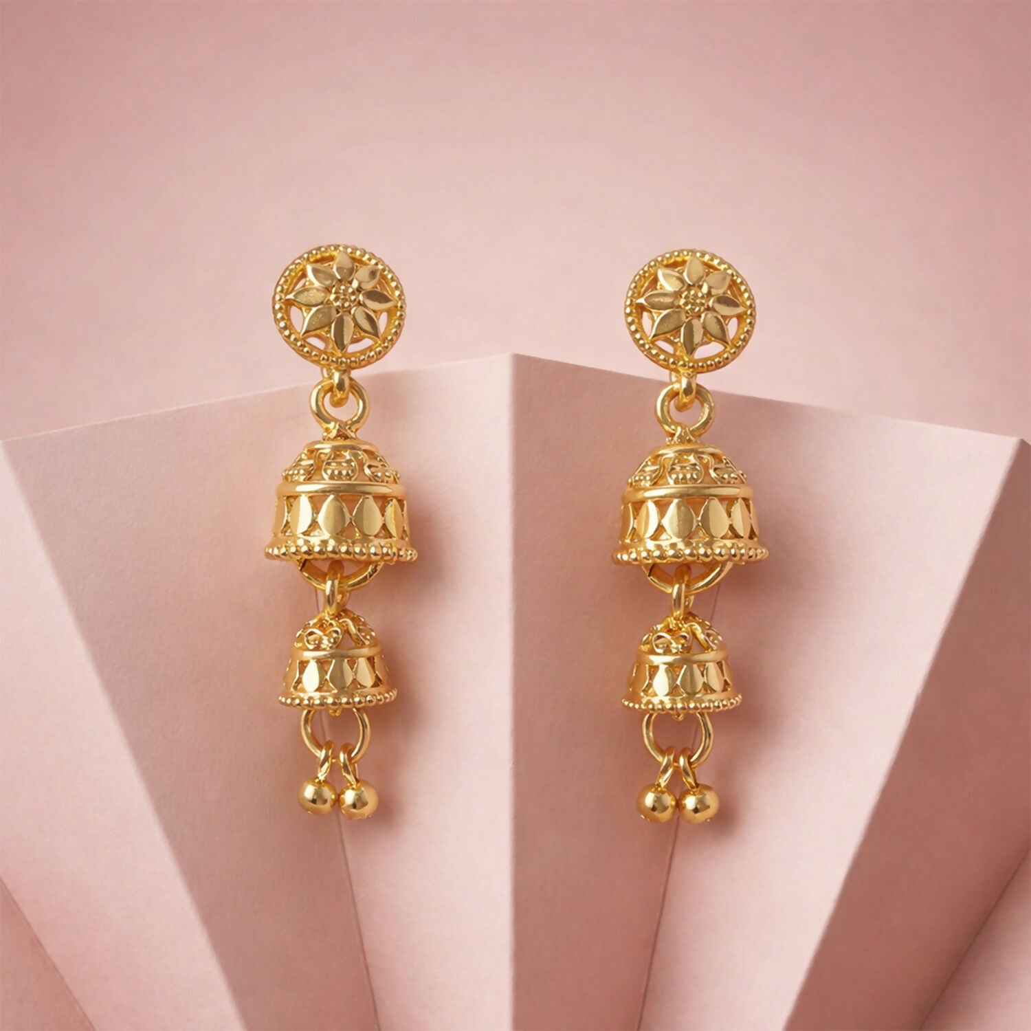 Pair of gold tone floral jhumka earrings on white background