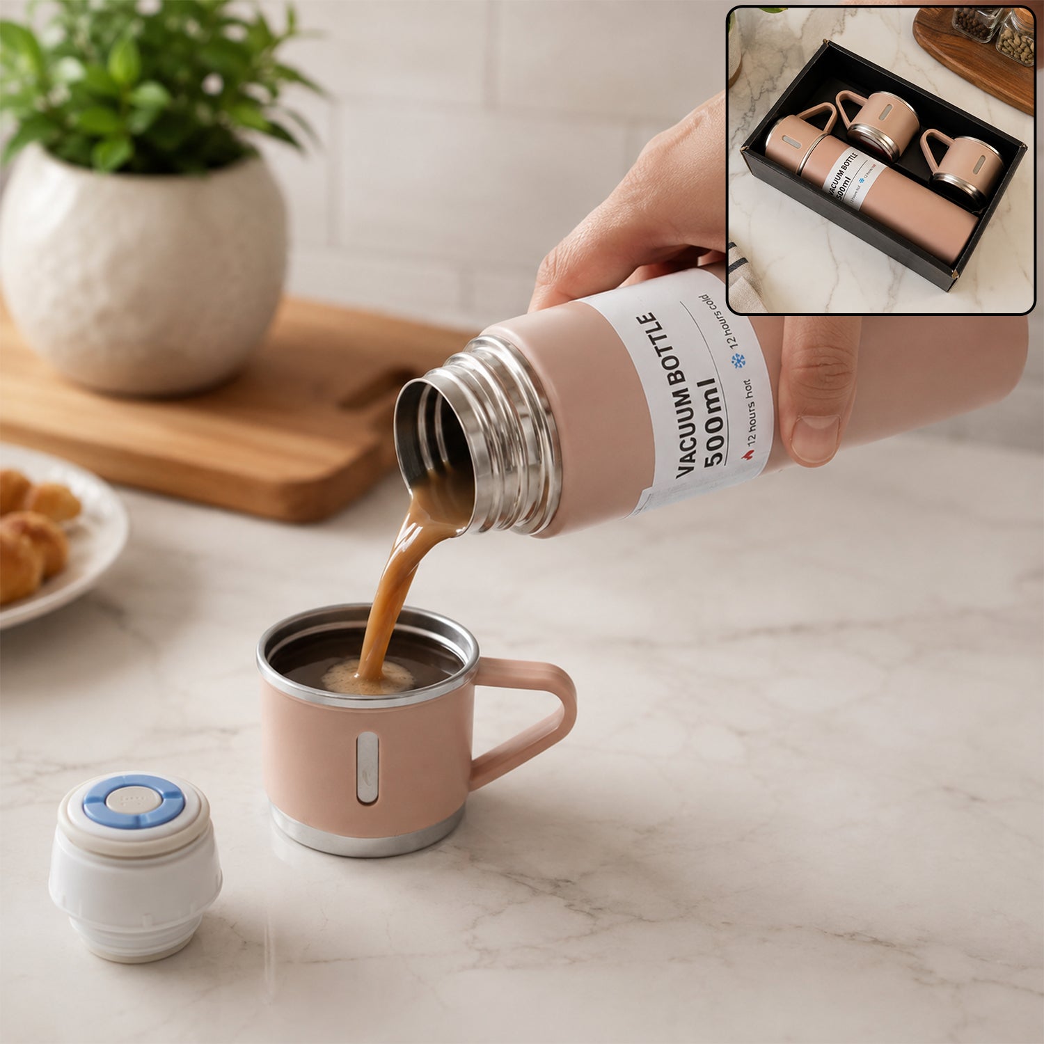 A hand pours coffee from a pink vacuum flask into a matching cup on a marble counter, with a small speaker and plant nearby.