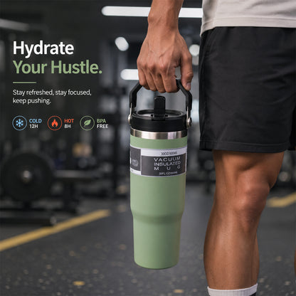 A person holds a green insulated tumbler with a handle in a gym setting.
