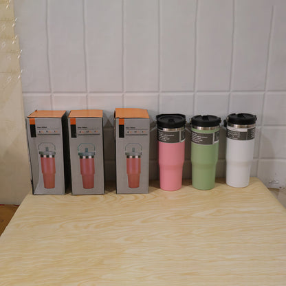 Three boxed pink tumblers and three unboxed tumblers in pink, green, and white sit on a wooden table.