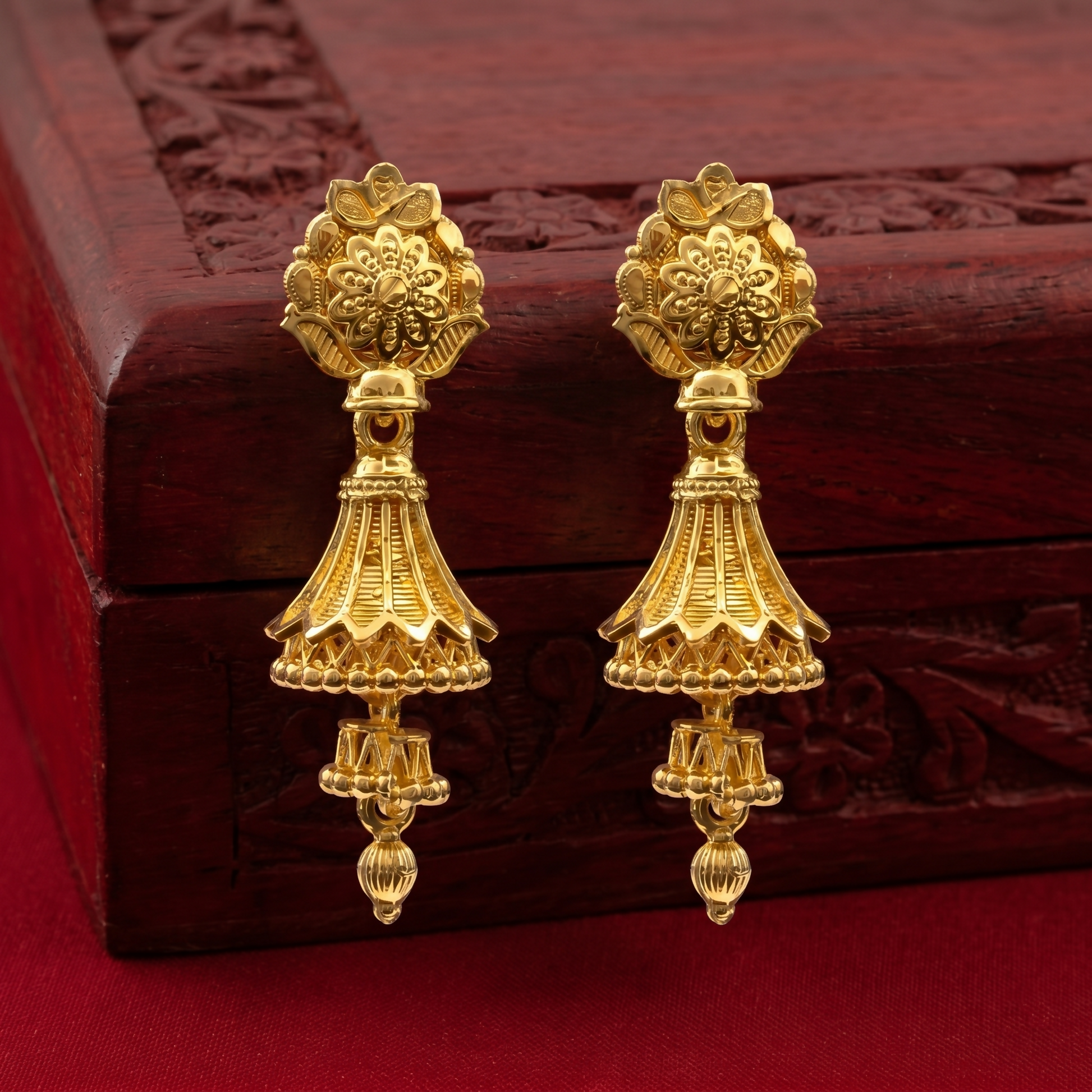 Pair of intricate gold jhumki earrings on a white background