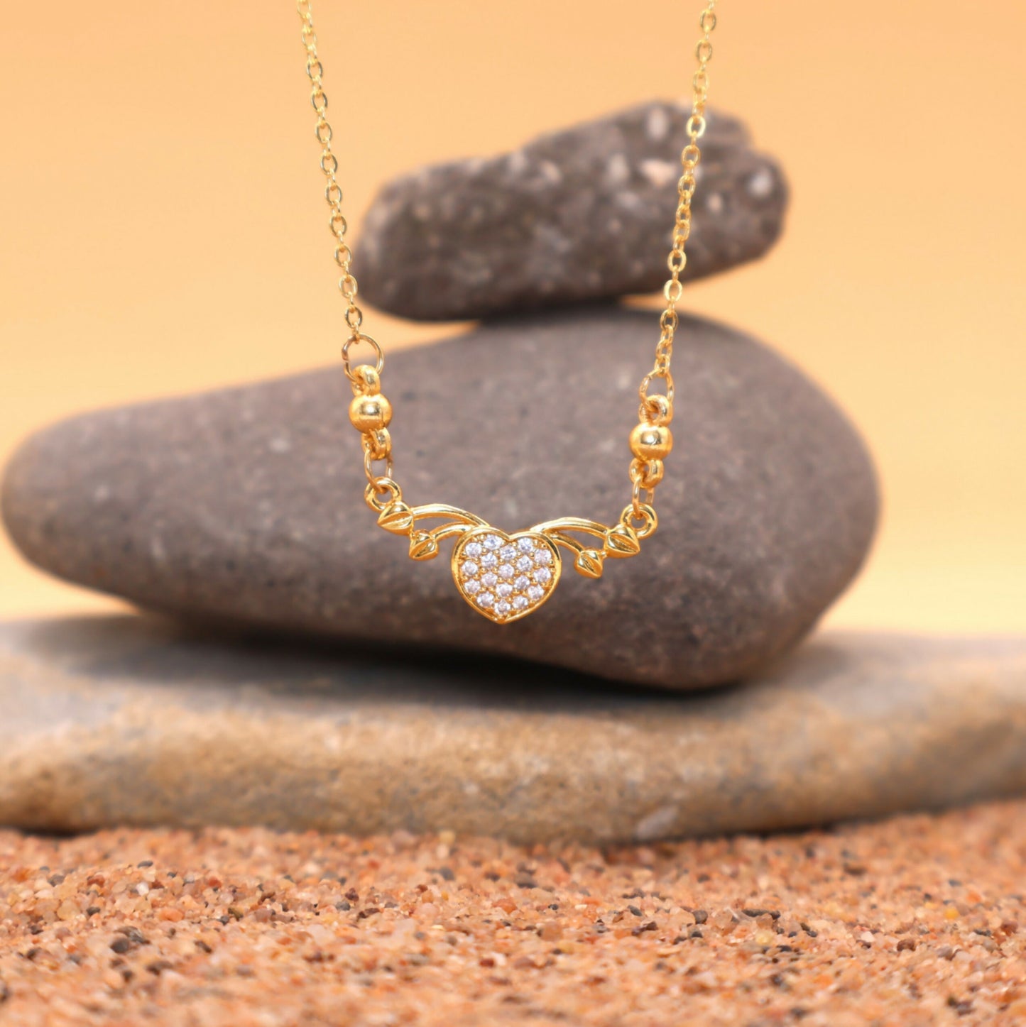 Close-up of gold heart necklace pendant with leaf-like gold accents and CZ stones