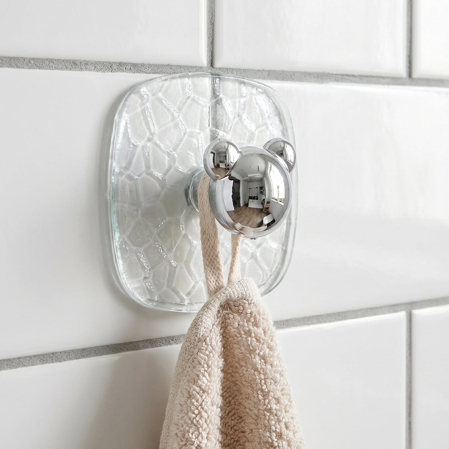 Close-up of clear plastic adhesive wall hook holding a kitchen towel