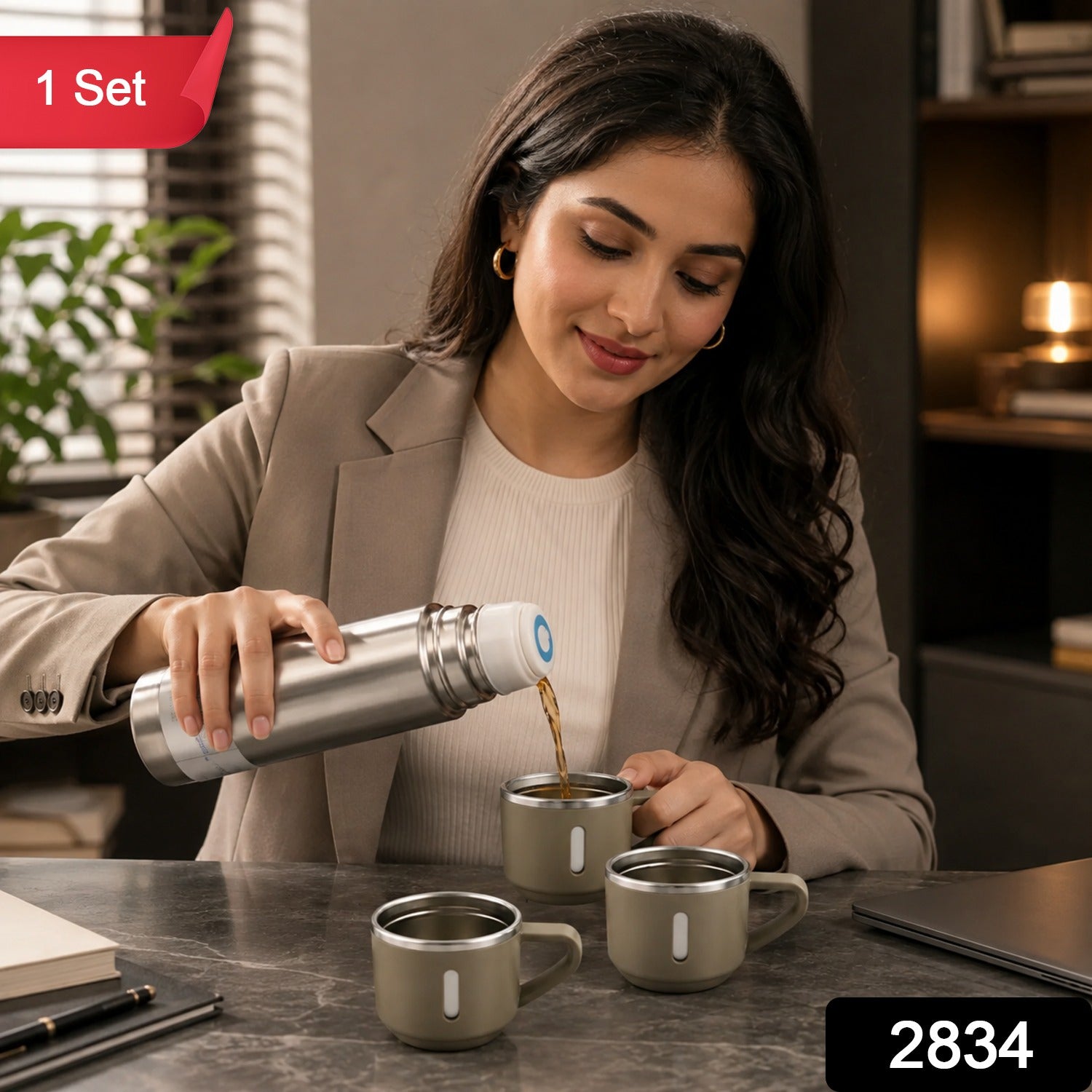 A woman pours coffee from a silver vacuum flask into a beige mug, with two other mugs nearby on a dark desk.