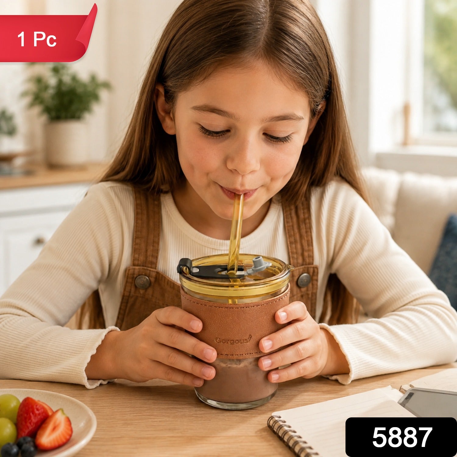 A young girl sips from an amber glass cup with a brown leather sleeve and a yellow straw, with a red "1 Pc" label and black