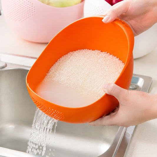 Hands hold an orange plastic bowl, draining water from rice into a stainless steel sink.
