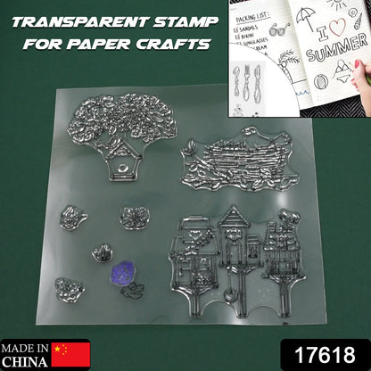 A clear rubber stamp sheet with designs of a tree, bird's nest, and birdhouses is displayed on a green background.