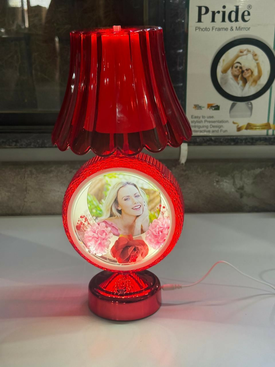 Red round photo table lamp shown on bedside table with warm light