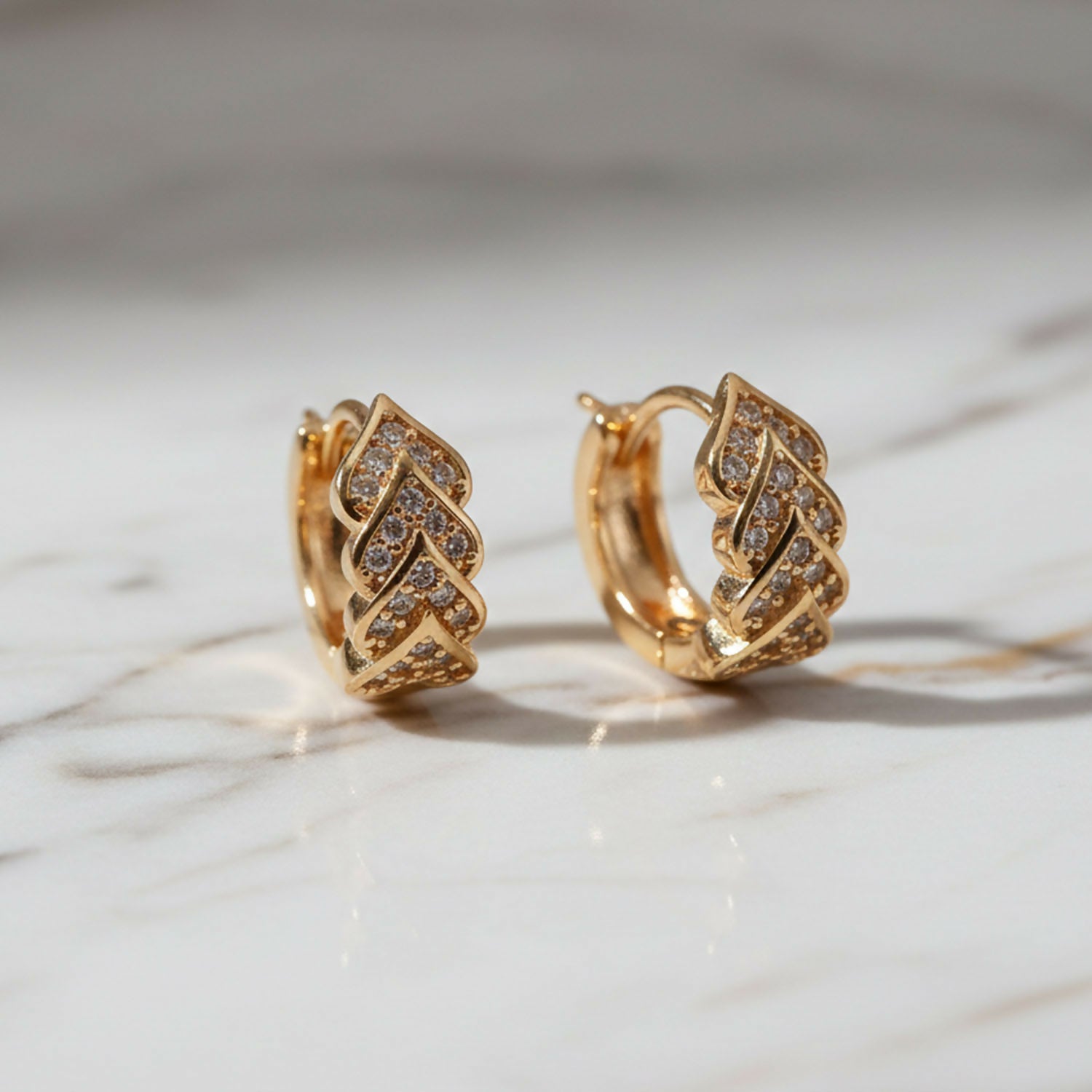 Pair of gold finish leaf pattern stud earrings displaying layered design and sparkle