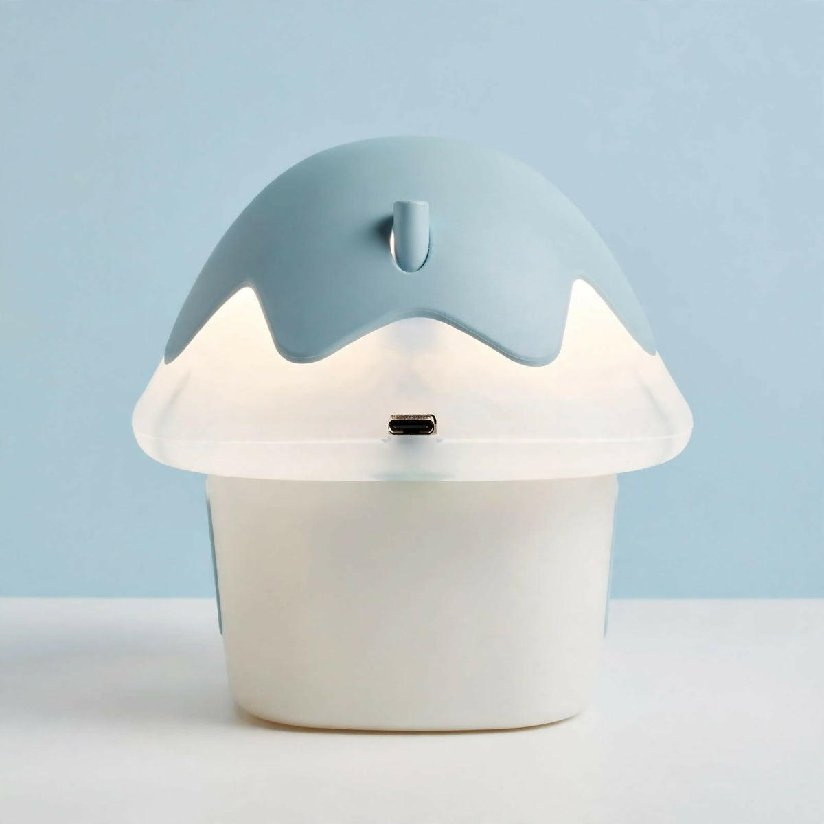 The back of a light blue and white mushroom house night light, showing a USB-C charging port on the cap.