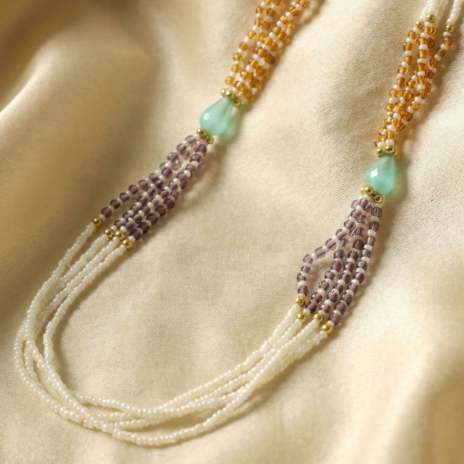 Side view of pearl necklace with green and lavender bead accents