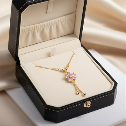 Elegant gold-tone chain featuring pink floral crystal pendant and twin drop tassels