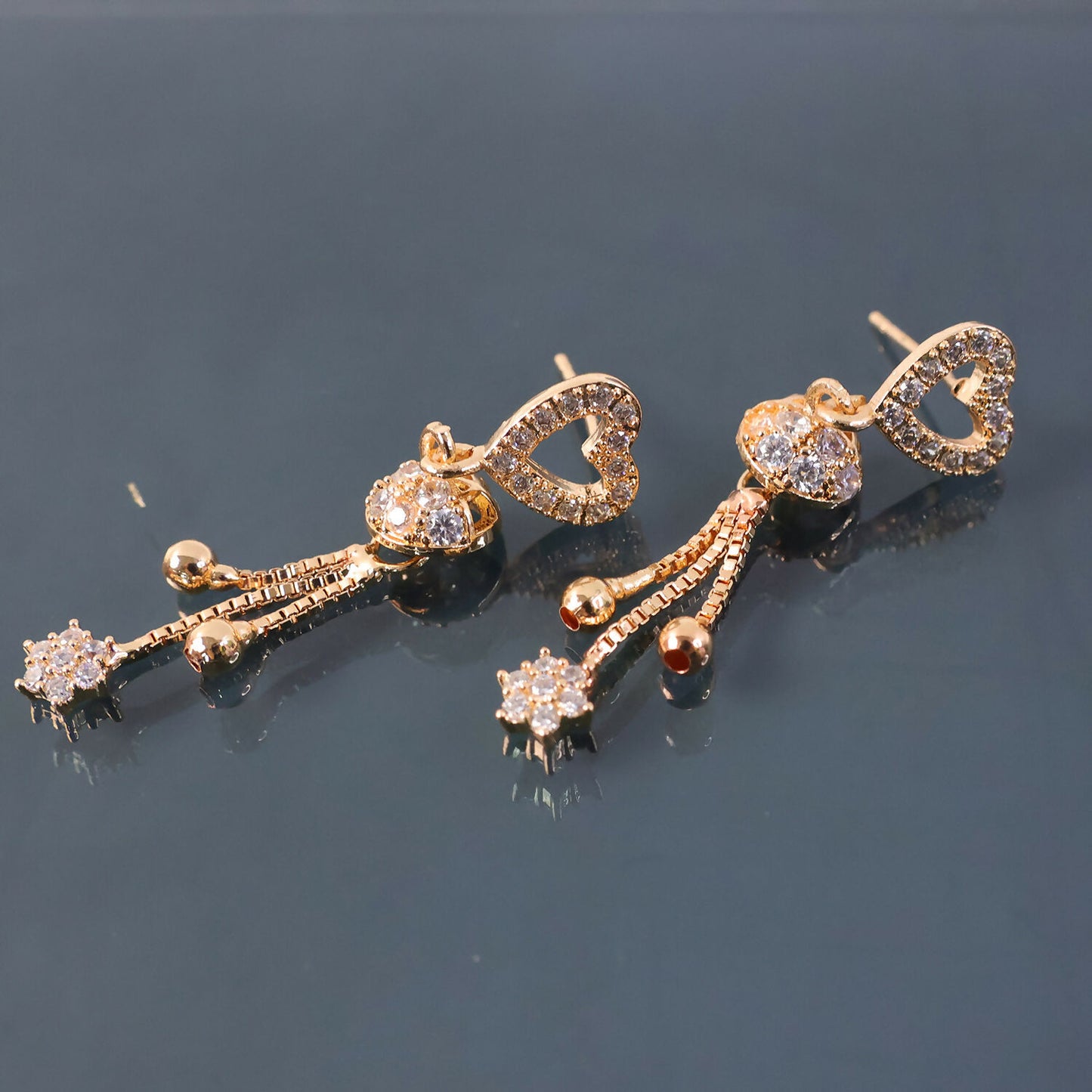 Fashion shot of rose gold crystal heart tassel earrings worn on ear