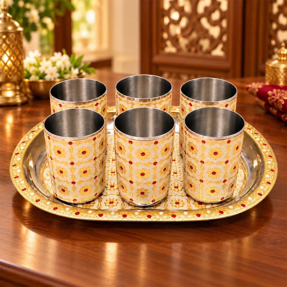 Six stainless steel glasses with a yellow and red floral pattern on an oval tray, displayed on a wooden table.