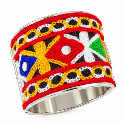 A wide silver cuff bracelet with vibrant embroidery and mirror work on a white background.