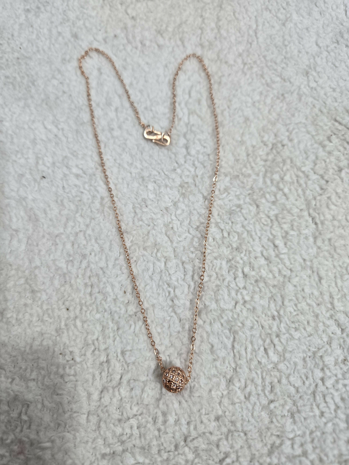 Detailed view of the gold-tone delicate chain and clear stone pendant