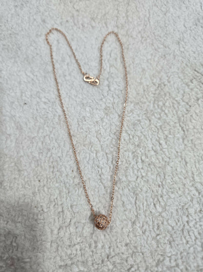 Detailed view of the gold-tone delicate chain and clear stone pendant