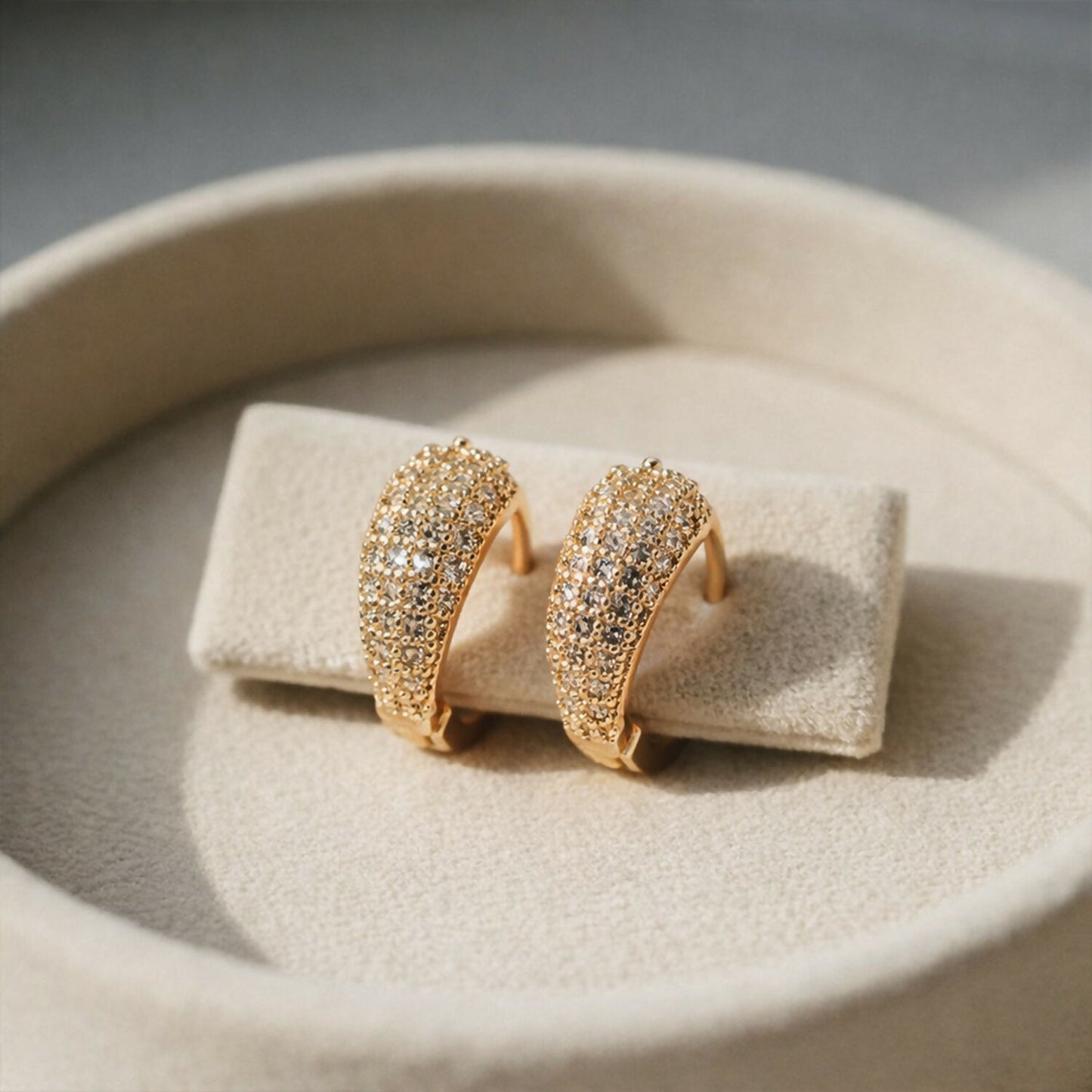 Close-up of dainty gold crystal huggie hoop earrings showing pavé crystal setting