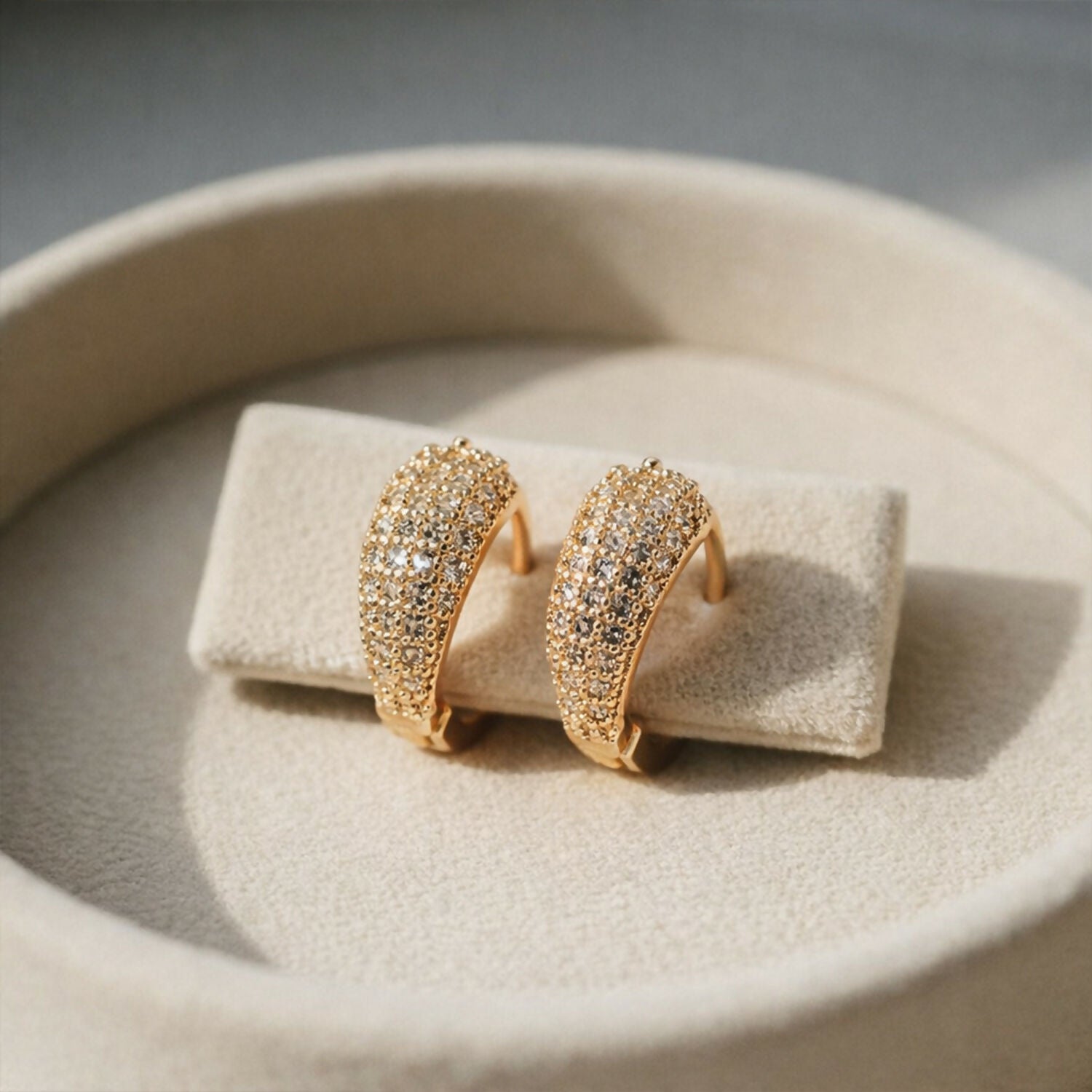 Close-up of dainty gold crystal huggie hoop earrings showing pavé crystal setting