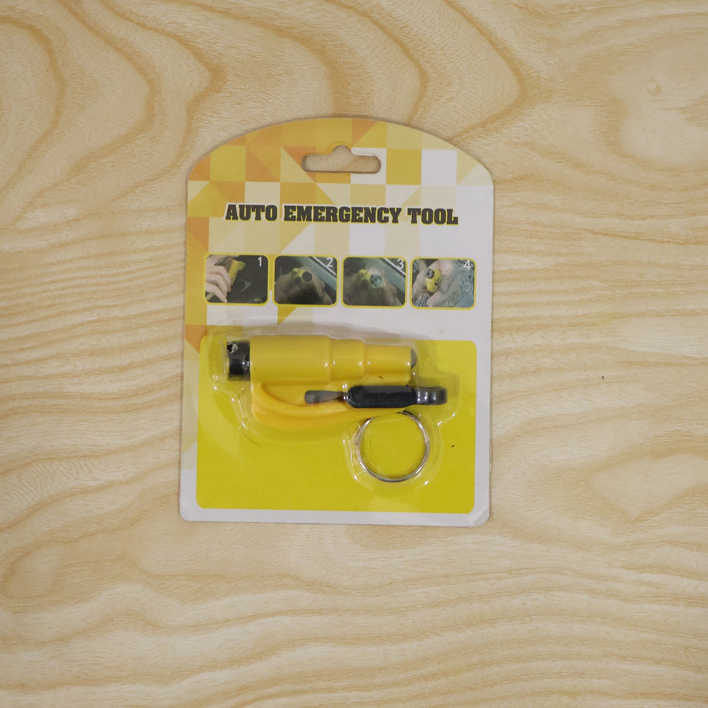The yellow auto emergency tool, a keychain car safety hammer, is displayed in its retail packaging on a light wooden