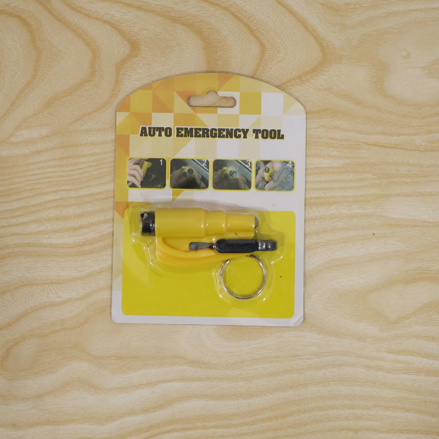 The yellow auto emergency tool, a keychain car safety hammer, is displayed in its retail packaging on a light wooden