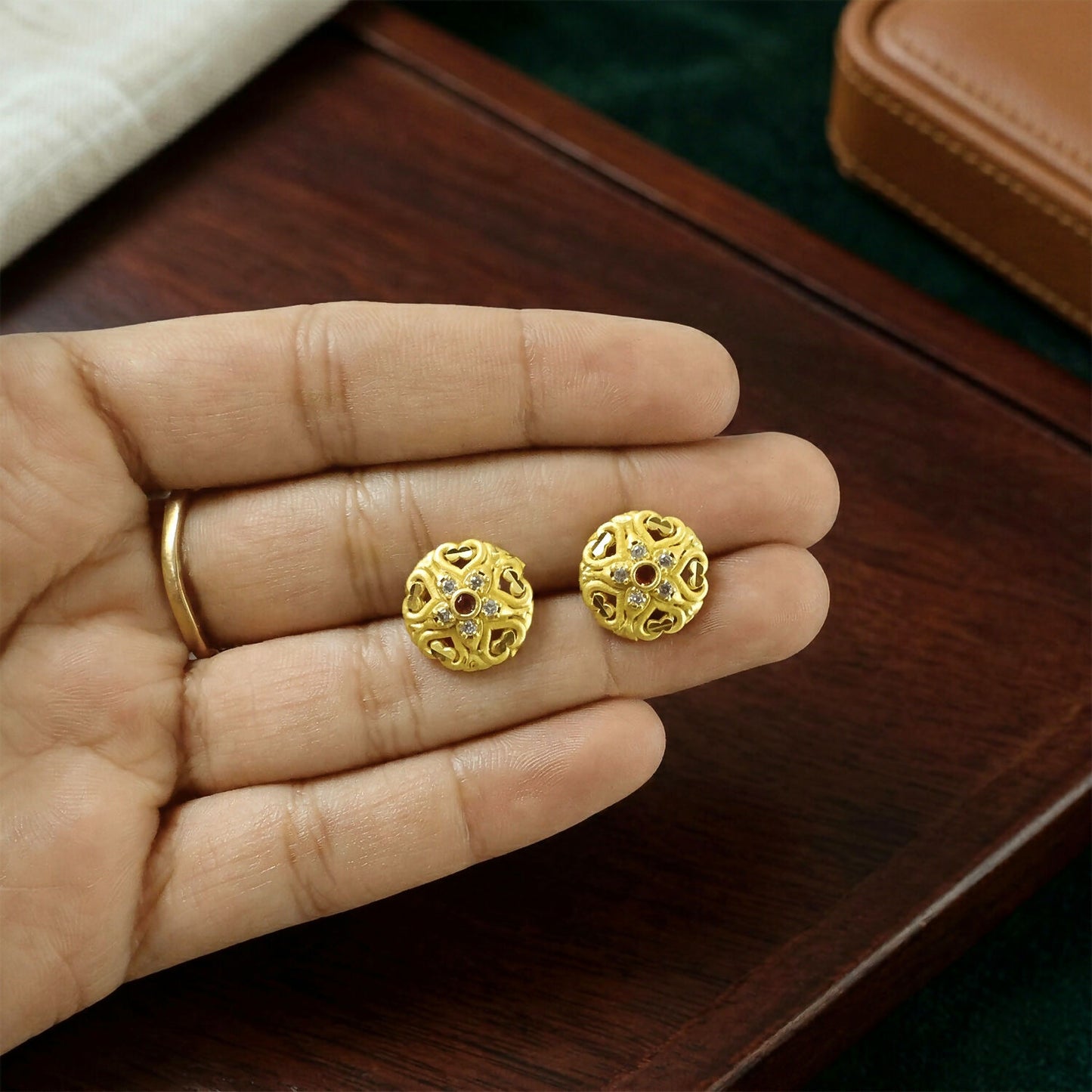 Front view of handcrafted gold earrings with detailed floral patterns