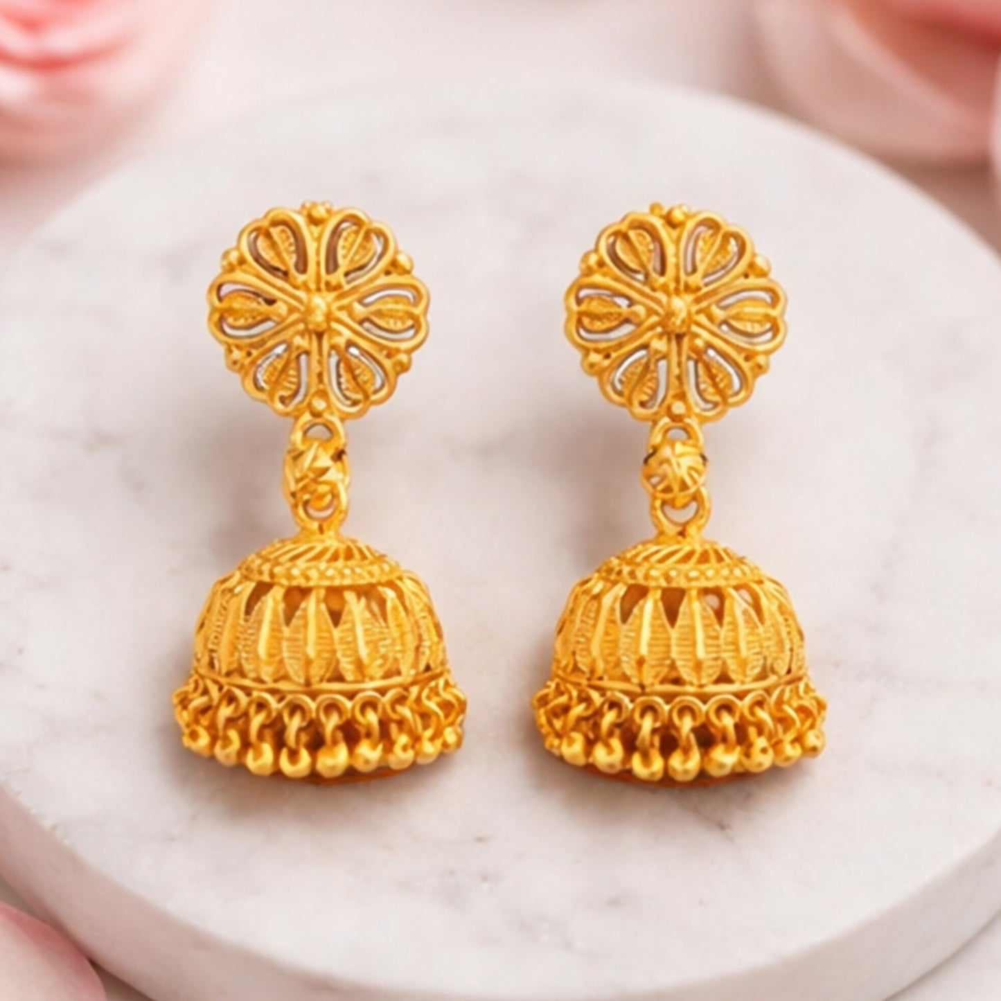 Close-up of gold plated jhumka earrings with traditional intricate design