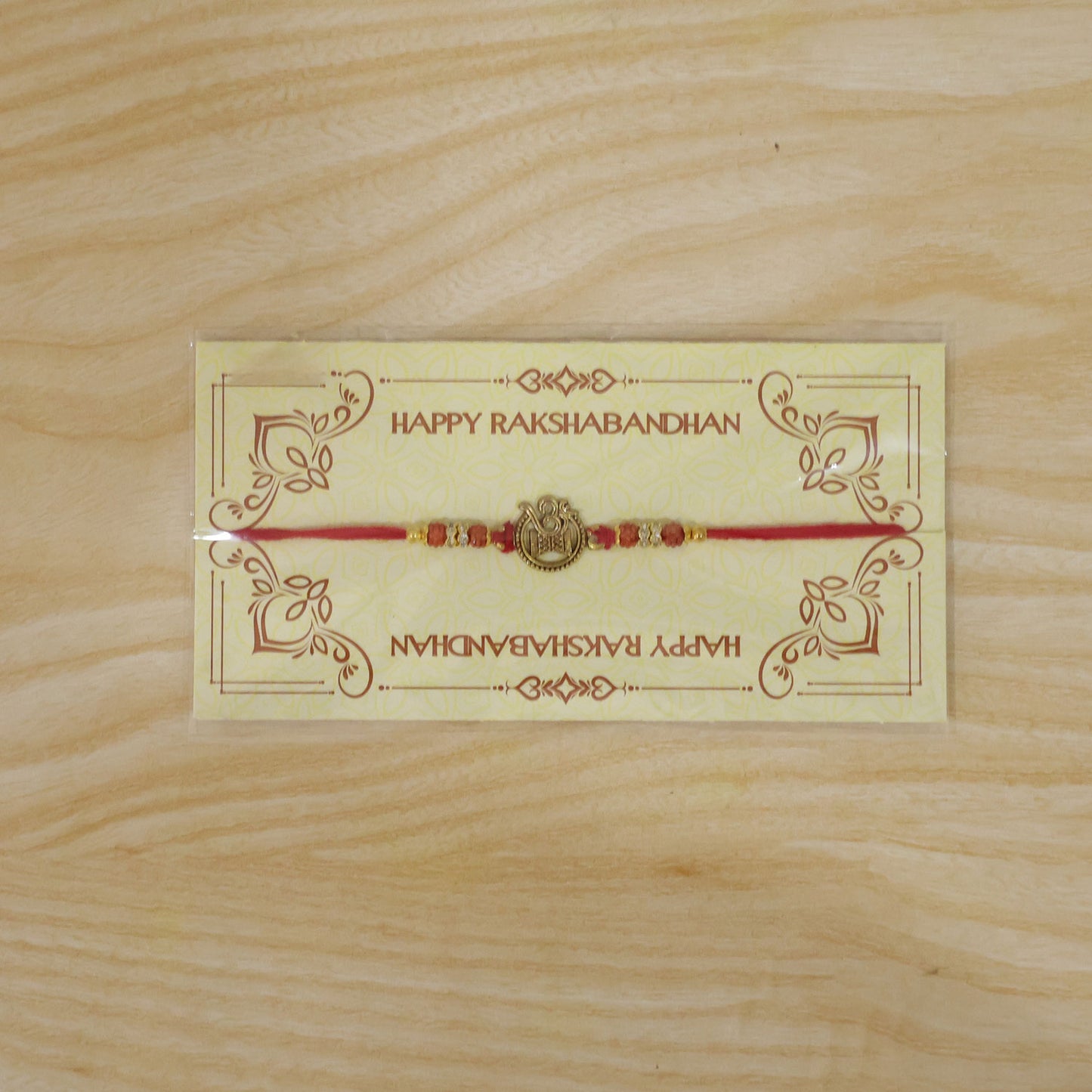 Om Damru Trishul Devotional Rakhi with Golden Centre, Orange Beads and Red Thread