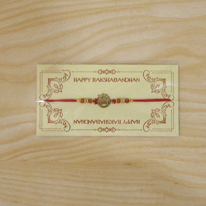 Om Damru Trishul Devotional Rakhi with Golden Centre, Orange Beads and Red Thread