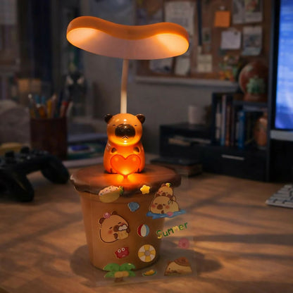 A brown koala desk lamp with glowing heart sits on a desk, decorated with playful stickers.