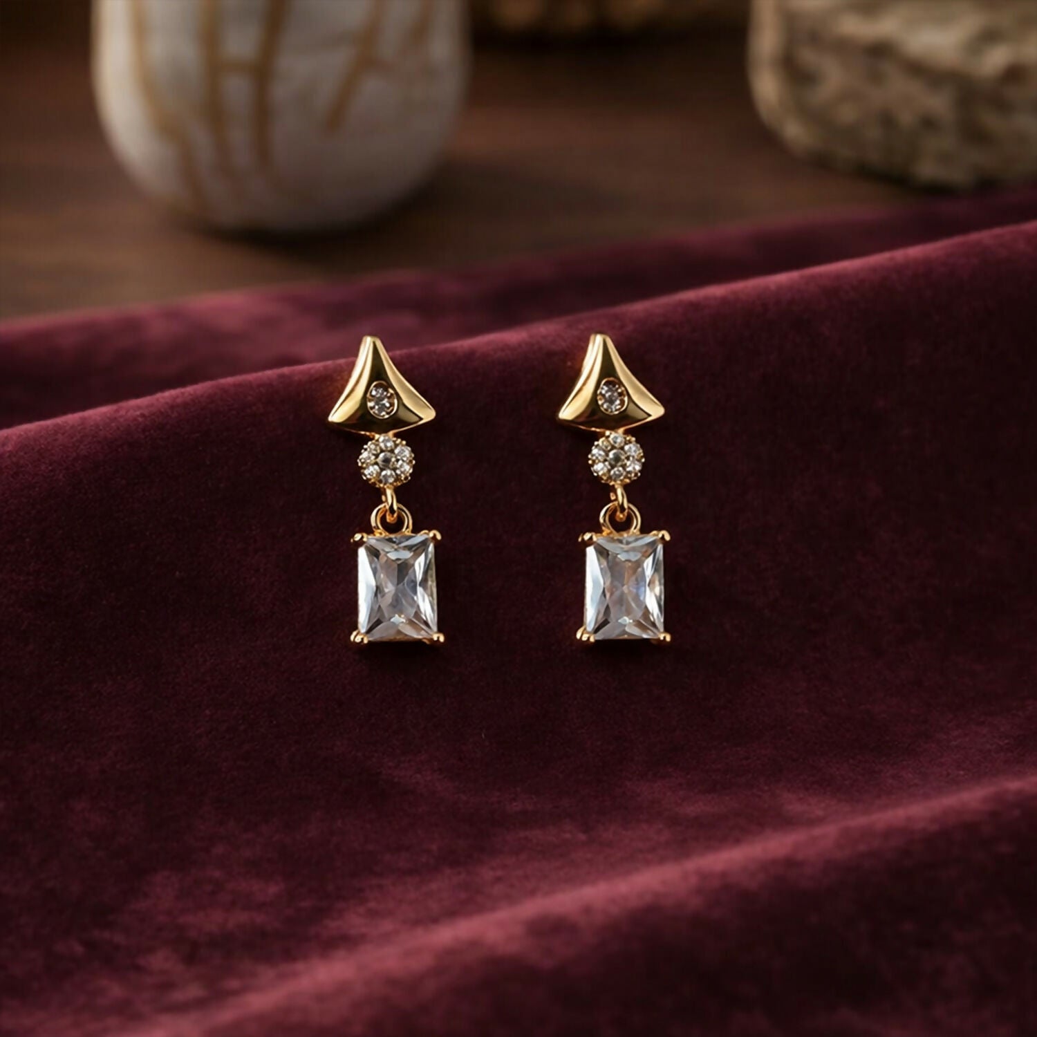 Gold tone crystal drop earrings featuring geometric triangular and rectangular shapes
