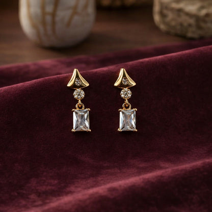 Gold tone crystal drop earrings featuring geometric triangular and rectangular shapes