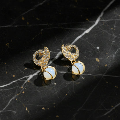 Swan earrings displayed on jewelry stand with light reflections