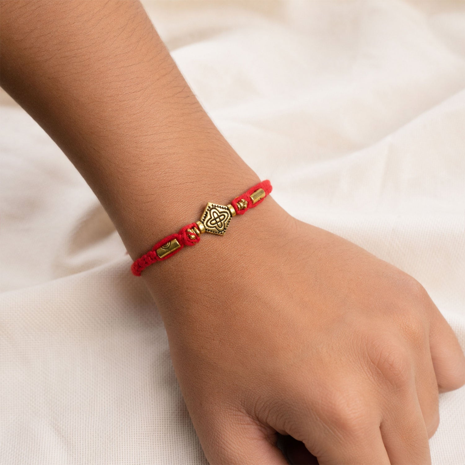 Red Thread Rakhi with an Intricately Detailed Antique Gold Charm