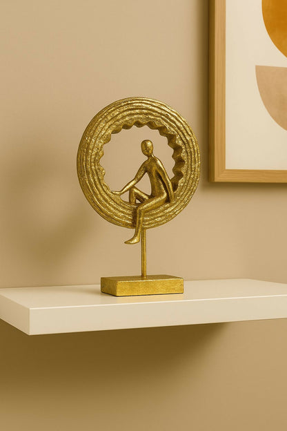 Golden yoga figurine statue displayed on shelf with ring backdrop